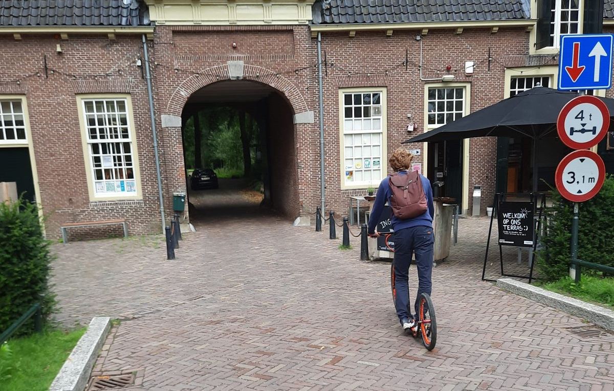 Iemand stept op een gehuurde kickbike door een oude stadspoort in Utrecht